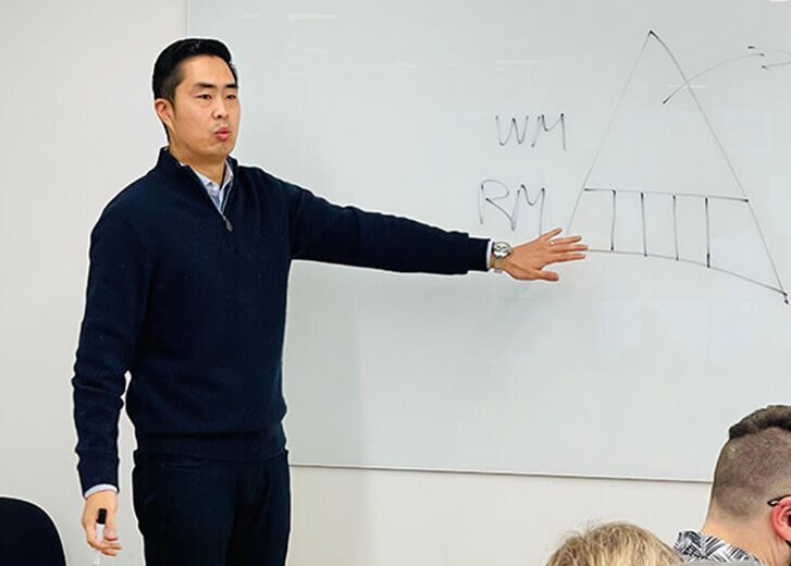 Wealth Management Advisor Richard Woo teaching finances on a whiteboard