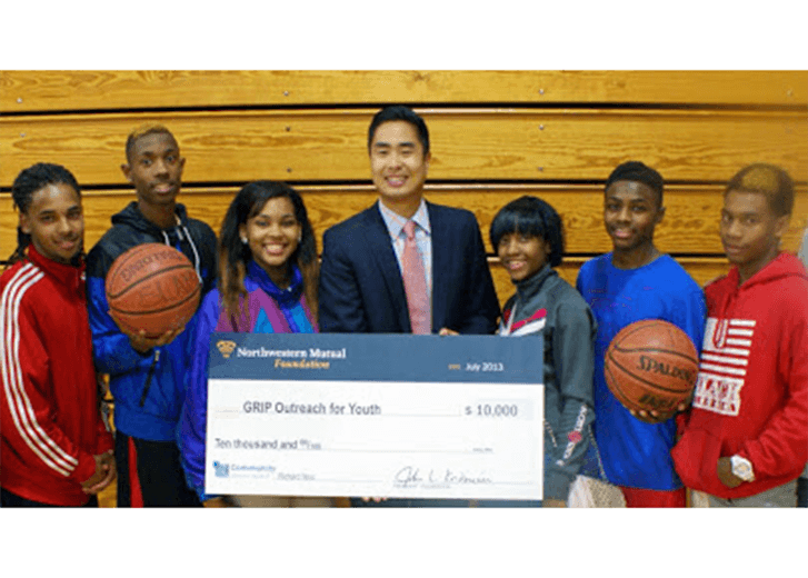 Rich holding a donation check for GRIP with basketball students